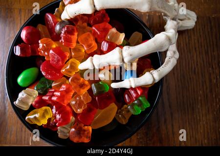 Skelett Kralle Hände mit Süßigkeiten und Hand Sanitizer - Halloween Konzept Stockfoto