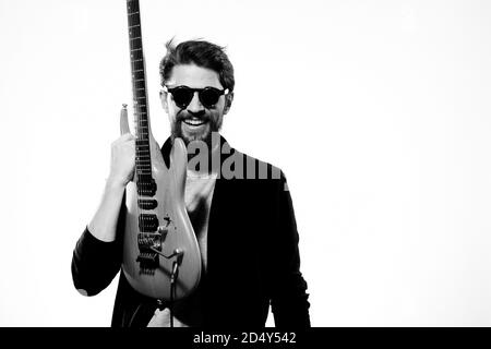 Ein Mann mit einer Gitarre Emotionen Musik Spiel Performance Leder Jacke Sonnenbrille Licht Hintergrund Stockfoto