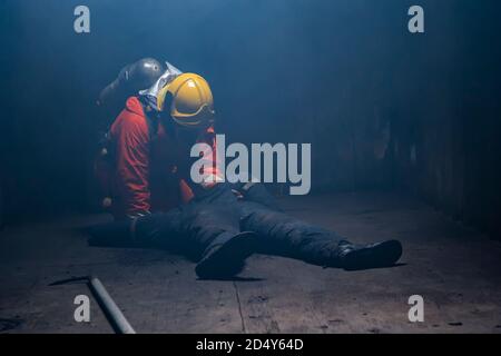 Feuerwehrmann helfen Menschen in der brennenden Lagerhalle / Feuerwehr und Rettungsschule regelmäßig nach Mach dich fertig. Stockfoto