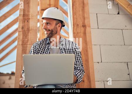 Fröhlicher junger Architekt mit seinem Laptop im Freien Stockfoto