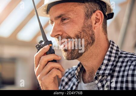 Junger männlicher Baumeister, der auf einem Walkie-Talkie kommuniziert Stockfoto