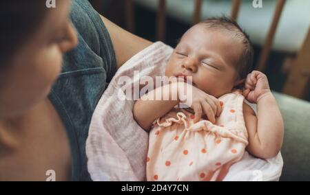 Neugeborenes Baby schläft in Sicherheit, während Mutter hält und Lächelt sie an Stockfoto