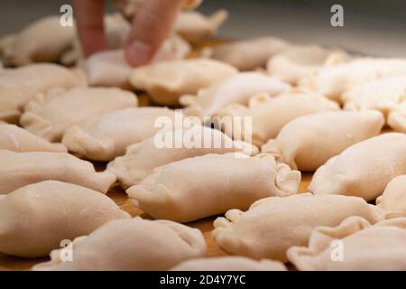 Weibchen legt rohe Knödel handgefertigt auf einem Holzbrett Stockfoto