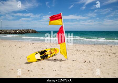 Perth, Australien - 7. Oktober 2020: Surf Rettungsschwimmer Flagge und Board am Strand von Cottesloe mit dem Meer im Hintergrund Stockfoto