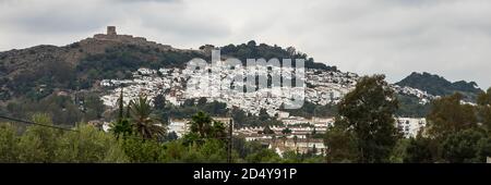 Blick auf das weiß getünchte Dorf, Pueblo Blanco und die umliegende Landschaft mit einem Schloss auf dem Hügel, Jimena de la Frontera, Provinz Cadiz, Andalu Stockfoto