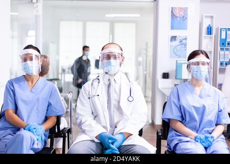 Medizinisches Personal in Klinik Wartebereich trägt Gesichtsmaske Schutz gegen Coronavirus Ausbruch als Sicherheitsmaßnahme. Medic trägt Stethoskop. Stockfoto