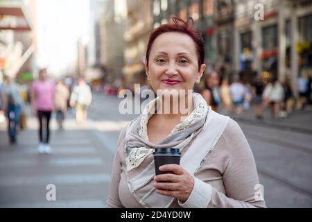 Frau in der Stadt. Schönes Porträt der älteren Frau mittleren Alters zu Fuß und halten Kaffeetasse im Freien Stockfoto