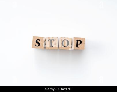 Ein Holzblock mit dem Wort STOP darauf geschrieben Auf weißem Hintergrund Stockfoto