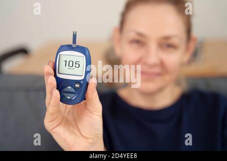 Kaukasische Frau mit Blutzuckermessgerät. Gesundheit mittleren Alters. Hyperglykämie-Konzept. Stockfoto