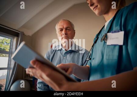 Nahaufnahme der weiblichen Hände des Arztes, die digitale Tablette mit Senior halten Patient Stockfoto
