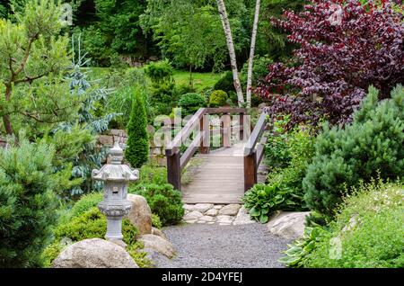 Blick auf den japanischen Garten mit geformten Bäumen, Steinen, Sand, Holzbrücke. Polen, Shklarska poreba. Selektiver Fokus. Stockfoto