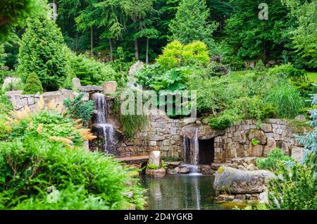 Japanischer Garten Blick auf Teich mit Wasserfall, Steinmauern und geformten Bäumen. Polen, Shklarska poreba. Selektiver Fokus. Stockfoto