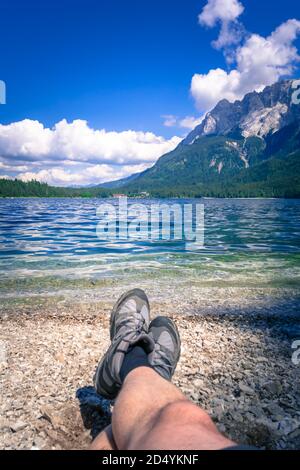 Füße mit Wanderschuhen am Ufer des Eibsee In Bayern Deutschland Stockfoto