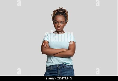 Irritierte junge schwarze Frau, die Kamera über grau anschaut Stockfoto