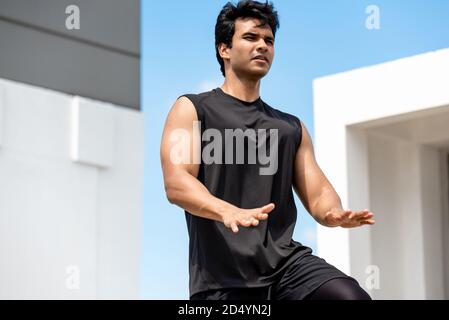 Schöner indischer Mann tun hohe Knie Tap Übung im Freien auf Gebäude Dach, Open Air Home Workout Konzept Stockfoto