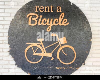 Schild „Rent a Bike“ an der weißen Backsteinmauer. Stockfoto