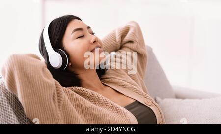 Asiatische Frau, die mit Kopfhörern Musik hört Stockfoto