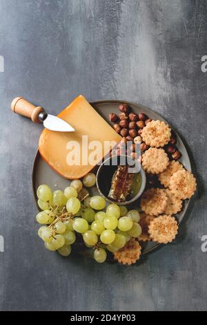 Wein Snack. Käse, Trauben, Nüsse, Käse, Cracker Kekse, Waben mit Messer über dunkle Textur Hintergrund. Flach, Raum Stockfoto