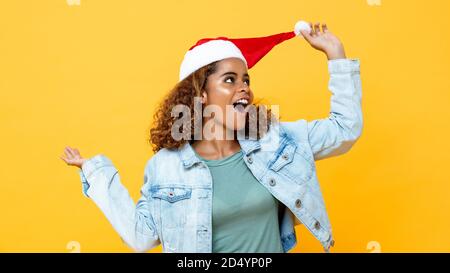 Spaß überrascht glücklich afroamerikanische Frau trägt Weihnachtshut auf Gelber isolierter Hintergrund Stockfoto