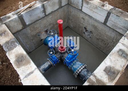 Schieber in der Schiebergrube der Erdleitungsnetze. Verlegung der Wasserleitung auf der Baustelle. Wasserleitung, Rohre in Graben Stockfoto