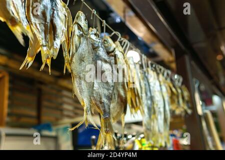 Getrocknete Flussfische hängen an Haken. Bier-Snacks und viel leckerer Fisch. Verkauf von Fisch auf dem Markt Stockfoto