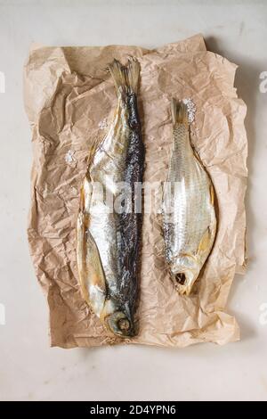 Getrocknete Fische oder Stockfisch auf zerknittertes Papier über weißem Marmor Hintergrund. Flach, Raum Stockfoto