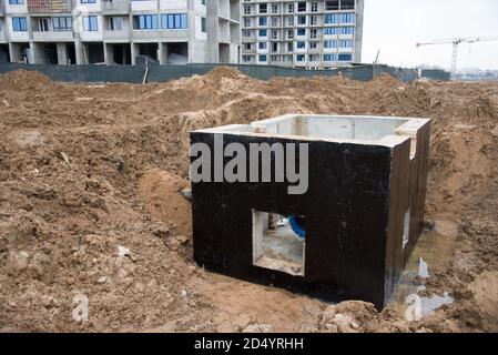 Ventilgrube für unterirdische Rohrleitungsnetze auf der Baustelle. Betonschachtringe und Ventilkammer Abwasserpumpstationen. Regenwasser aufbauen Stockfoto