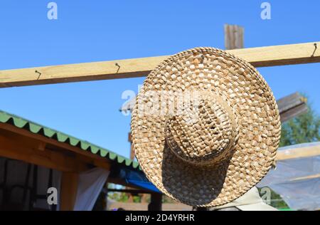 Strohhut, der auf einem hölzernen Kleiderbügel hängt Stockfoto