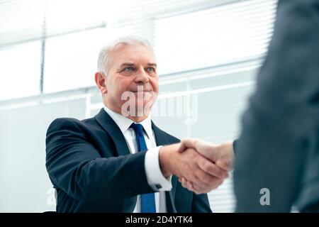 Firm Business Handshake auf einem verschwommenen Bürohintergrund. Stockfoto