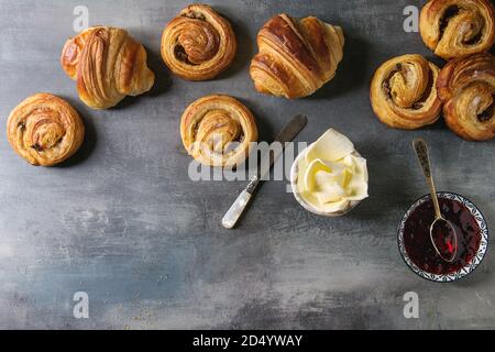 Auswahl an hausgemachten Blätterteig brötchen Zimt Brötchen und Croissant mit Marmelade, Butter als Frühstück über blaue Textur Hintergrund serviert. Flach, Raum Stockfoto