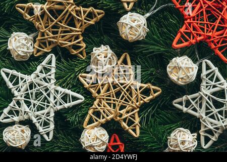 Festlicher Hintergrund von Tannenzweigen mit einer Girlande und Dekorationen in Form von bunten Sternen. Weihnachtsbanner. Nahaufnahme. Speicherplatz kopieren. Stockfoto