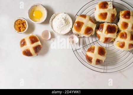 Hausgemachte Ostern traditionelle Hot Cross Buns auf Kühlung Rack mit Zutaten oben auf weißem Hintergrund. Ansicht von oben, Raum Stockfoto