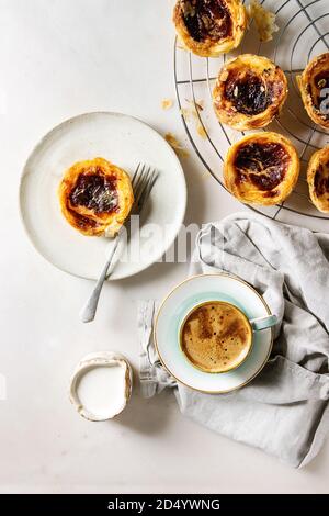 Traditionelle portugiesische Ei tart Dessert Pasteis Pastel de nata auf Kühlung Rack- und Keramik Teller mit Gabel, Tasse schwarzen Kaffee und Krug von Creme über Stockfoto