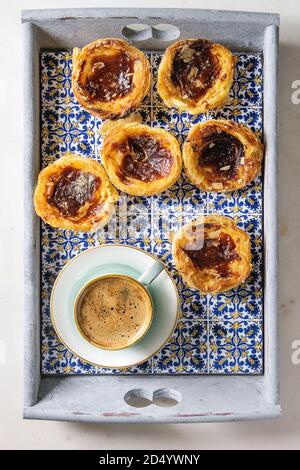 Traditionelle portugiesische Ei tart Dessert Pasteis Pastel de nata im klassischen Fliesen Fach mit Tasse schwarzen Kaffee. Flach, Raum Stockfoto