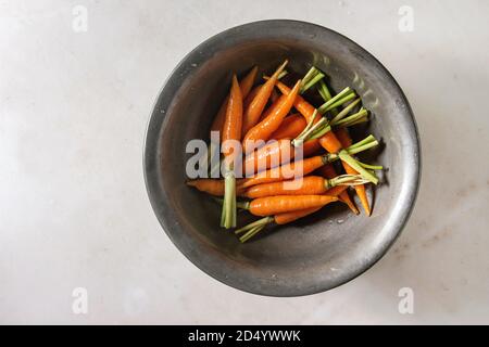 Junge mini Karotten in Vintage metall Schüssel über weißem Marmor Hintergrund. Flach, Platz. Kochen, essen Hintergrund. Stockfoto