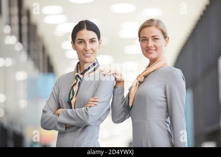 Wast up Porträt von zwei eleganten Flugbegleiter Blick auf Kamera und lächeln beim Posen im Flughafen Stockfoto