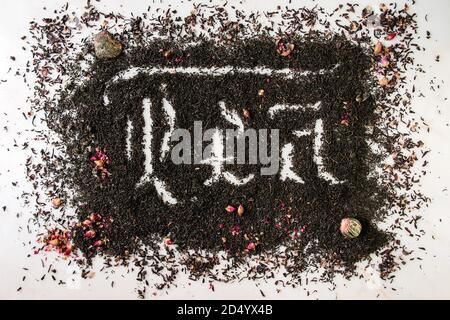 Kalligraphische Inschrift gotischen Buchstaben Kaffee über trockenes schwarz Ceylon und grüner Tee auf weißem Marmor mit Rosenknospen verstreut. Kaffee trinken Konzept backgro Stockfoto