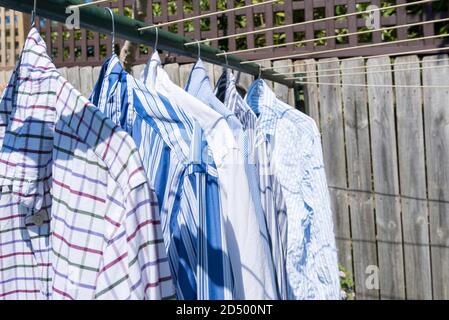 Eine Sammlung von bunten Business-Shirts hängen mit Kleiderbügel An einer Wasch- oder Wäscheleine in der australischen Sonne Stockfoto