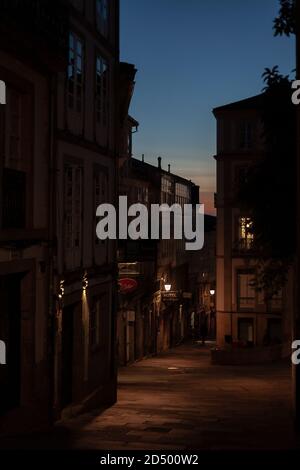 Rustikale ruhige schmale Straßenlampe beleuchtete Straße in der Altstadt von Santiago de Compostela in der Dämmerung. Galicien, Spanien. Stockfoto