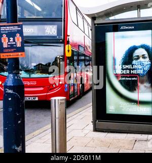 London UK Oktober 10 2020, Red Double Decker London Bus Pasting Bushaltestelle mit EINEM COVID-19-Poster Stockfoto