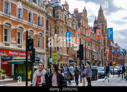 Zwei lächelnde Damen überqueren die Oxford Street in der Duke Street. Auf der anderen Straßenseite gibt es Schilder, die Danke sagen, Schlüsselarbeiter und Sie sind wahre Helden. West End, London, Großbritannien Stockfoto