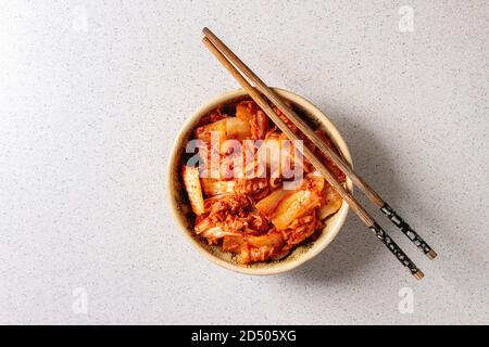 Traditionelle koreanische fermentiert Vorspeise kimchi Speck-krautsalat in Keramik Schüssel mit shopsticks über Grau gefleckten Hintergrund. Flach, Platz. Stockfoto