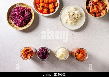 Vielzahl von fermentierter Lebensmittel traditionellen koreanischen Kimchi Kohl und Rettich Salat, Weiß und Rot, Sauerkraut in Glas und keramische Platten über graue Fleck Stockfoto
