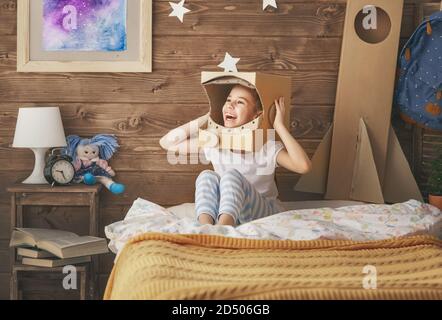 Kind Mädchen im Astronaut Kostüm mit Spielzeug Rakete spielen und träumen von einem Raumfahrer zu werden. Portrait von lustigen Kind im Schlafzimmer. Stockfoto