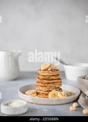 Hausgemachte Haferpfannkuchen mit Banane und Nüsse. Grauer Hintergrund, vertikales Bild Stockfoto