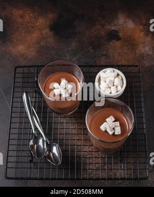 Schokoladendessert (Panna Cotta, Mousse oder Pudding) in portionierten Tassen. Dunkler Hintergrund, Seitenansicht Stockfoto
