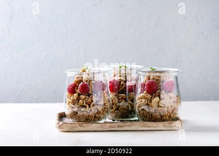 2-in-1-Dessert in Töpfen. Keks, Kaffeesahne, Muttern, Himbeeren, frischer Minze. Auf keramischen Fach über weißem Marmor Tisch serviert. Stockfoto