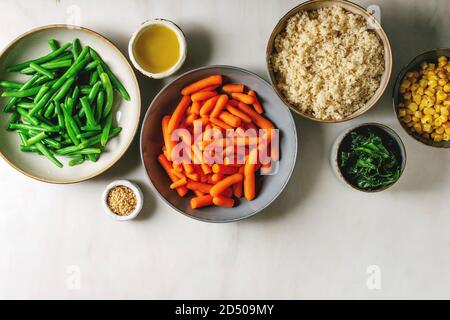 Couscous mit parboiled Gemüse Karotten, grüne Bohnen, Mais, Spinat in separaten Keramische Platten mit Sesam und Olivenöl. Vegan fo Stockfoto