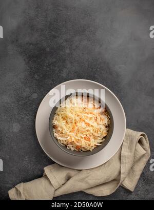 Schüssel mit hausgemachtem Sauerkraut. Probiotisches Lebensmittelkonzept. Dunkelgrauer Hintergrund, Draufsicht, vertikales Bild Stockfoto
