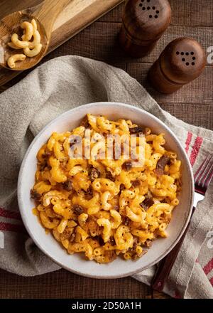 Schüssel mit Makkaroni und Käse mit Speckstücken auf einem rustikalen Holztisch. Overhead-Ansicht Stockfoto